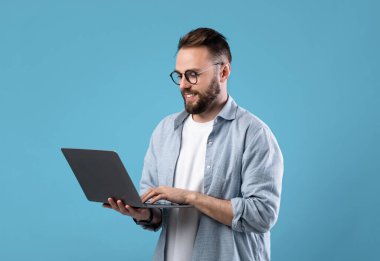 Gözlüklü genç adam bilgisayarını internet işi için kullanıyor ya da mavi stüdyo geçmişi ile iletişim kuruyor. Başarılı bir milenyum adamı Webinar 'a katılıyor, uzaktan görüşme yapıyor.