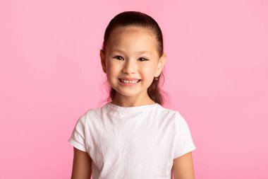 Tatlı Çocuk. Mutlu Asyalı çocuğun yakın plan fotoğrafı pembe stüdyo arka planında izole edilmiş kameraya bakıyor.