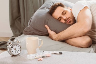 Adam uyku hapları aldıktan sonra yatakta dinleniyor, ilaçsa evdeki yatak odasında alarmın yanında yatıyor. Uykusuzluk ve uykusuzluk tedavisi, iyi bir uyku ilacı. Seçici Odaklanma, Sığ Derinlik