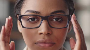 Gözlüklü bir Afrikalı Amerikalı kadın çevrimiçi öğretmenlik yaparken kameraya odaklanıyor. Uzaktan eğitime modern bir yaklaşım sergiliyor..