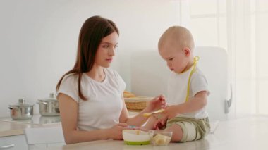 Yeni yürümeye başlayan bir çocuk, parlak bir mutfakta bir bakıcı ile atıştırma zamanı geçirir. Çocuk masada rahatça oturup anın tadını çıkarırken bir kase yiyeceği yakından inceler..