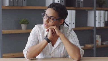 Kendini işine adamış bir öğretmen çevrimiçi bir ders için hazırlanırken derin düşüncelere dalmıştır. Modern ve aydınlık bir çevrede eğitim malzemelerinin raflarıyla çevrili..