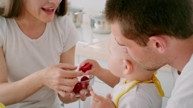 Neşeli yeni yürümeye başlayan bir çocuk, zevkle ikram edilmek için ağzını açan annesine çilek ikram eder. Bu yürek ısıtan an sıcak, davetkar bir mutfakta aile bağlarını yakalıyor..