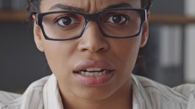 Gözlüklü bir Afrikalı Amerikalı kadın, öğrencilerine uzaktan öğretirken kararlı bir ifade sergiliyor.
