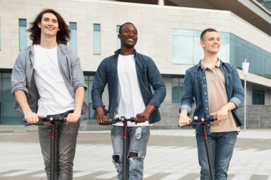 Özgürlük kavramı. Şehirde motorlu scooterlarla gezen üç farklı genç adam.