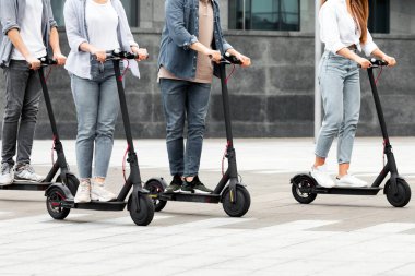 Dört farklı arkadaşın birlikte vakit geçirmesi şehirde elektrikli mobiletlerle dolaşması, yan görüş.