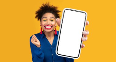 Mobil Teklif. Sarı Stüdyo Arkaplanı Üzerinde Cep Telefonu Pozisyonu İçin Harika Bir Uygulama Gösteren Büyük Akıllı Telefon Gösteren Neşeli Siyah Kadın. Yeni Uygulama Reklamı. Mockup, Panorama