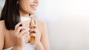 Saç ürünleri. Saç spreyi kullanan, fotokopi çeken, tanınmayan Asyalı kızın yakın çekimi.