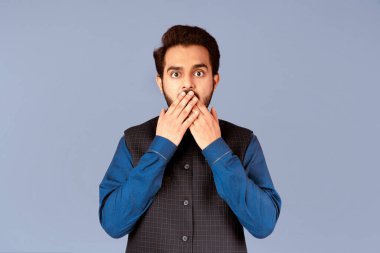 Hadi canım. Hintli adam menekşe arka planına karşı elleri ile ağzını kapatıyor. Panorama