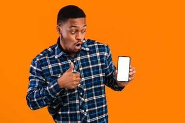 Harika Mobil Uygulama. Akıllı Telefon Gösteren Afrikalı Adam Boş Ekran Hareketi Başparmaklarını Sarı Arkaplan Üzerine Kaldırıyor. Stüdyo Çekimi, Model