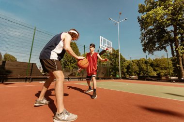 Milenyum basketbol oyuncuları hareketlerini açık hava spor stadyumu fotokopi salonunda birlikte yapıyorlar. İki profesyonel sporcu arkadaşça oyun oynuyor, sokak basketbolunun keyfini çıkarıyorlar.