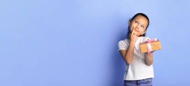 Bil bakalım içeride ne var? Heyecanlı Asyalı kız elinde gudt kutusuyla turkuaz stüdyo duvarında izole edilmiş şu anını düşünüyor.