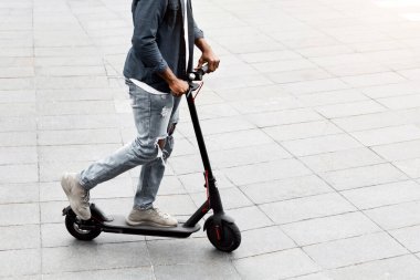 Hareket kabiliyeti kavramı. Gülümseyen zenci hipster 'ın yüksek açılı görüntüsü açık havada motorlu scooter sürüşü, serbest alan