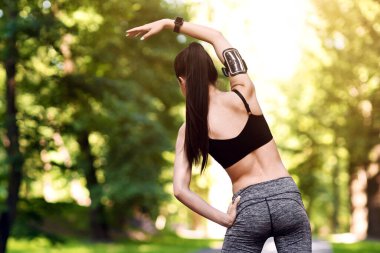 Spor salonu açık havada. Parkta koşmadan önce sportif bir kadının tam boy ısınma sahnesi.