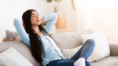 Tembel hafta sonu. Sakin Koreli kadın arkasını yaslıyor, gözleri kapalı, evinde dinleniyor, oturma odasında rahat bir kanepeye uzanıyor, elleri başının arkasında, Demestic Hobi 'nin tadını çıkarıyor, boşluğu kopyalıyor.