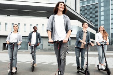 En iyi arkadaşlar. Kentsel alanda elektrikli scooter kullanan beş çok kültürlü gencin tam boy portresi.