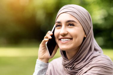 Telefonla konuşan, fotokopi alanına bakan mutlu müslüman kadının yakın plan portresi.