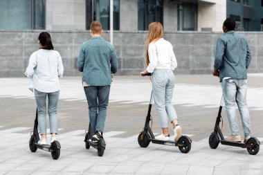 Bir grup farklı genç, güpegündüz düzgün bir şehir sokağında scooter sürüyor. Genç sürücüler rahat giyiniyor ve canlı bir gençlik kültürü sergiliyorlar.