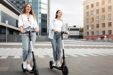 İki genç kız bir şehir caddesinde scooter 'a biniyor, açık havanın tadını çıkarıyorlar. Sıradan giyinmişler ve canlı bir şehir ortamında eğleniyorlarmış gibi görünüyorlar..
