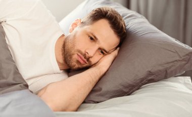 Erkek Depresyonu Konsepti. Uykusuzluk çeken duyarsız bir adam evde yatakta uzanan sorunları düşünüyor. Boşluğu Kopyala