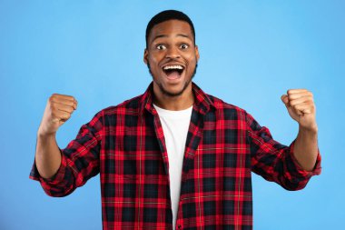 Heyecanlı Afrikalı Adam Titreyen Yumruklar Mavi Stüdyo Arkaplanındaki Başarı Pozisyonunu Kutluyor. Zaferin neşesi.