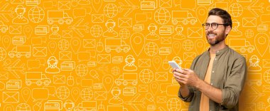 Alıcı internetten alışveriş yapmak için akıllı bir telefonla bağlantı kuruyor, teslimat ve ticari simgelerle dolu canlı bir arka plan sergiliyor. Bu dijital alışverişin modern kolaylığını temsil ediyor..