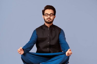 Stres yönetimi konsepti. Sakin Hintli adam eflatun arkaplan üzerinde gözleri kapalı meditasyon yapıyor. Panorama