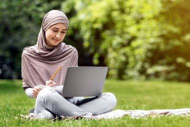 Kamu parkında dizüstü bilgisayarda çalışan Arap kadın serbest yazar, boşluğu kopyala