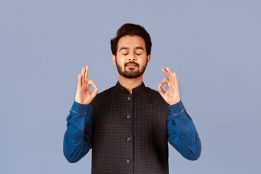 Huzurlu Hintli adam meditasyon yapıyor ve eflatun arka planda yoga yapıyor.