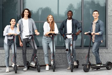 Motosikletli beş gülen öğrenciden oluşan çok ırklı bir grubun tam boy portresi.