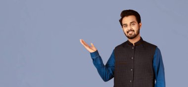 Gülümseyen Hintli adam menekşe arka planda ürün tasarımınız için bir şey sunuyor. Panorama