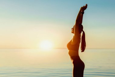 Sabah Eğitimi Konsepti. Spor kızı portresi ısınıyor, gün ışığında kumsalda ellerini uzatıyor.