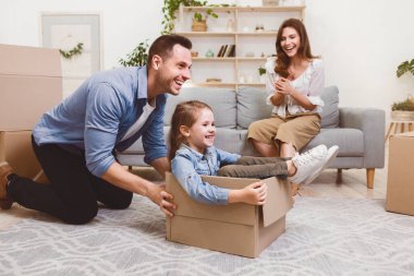 Aile Taşınma Konsepti. Baba taşınma kutusunda kızına biniyor ve yeni evinde eğleniyor. Seçici Odaklanma