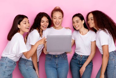 Çok Irklı Kadınlar Grubu Laptop Bilgisayar kullanarak Pembe Stüdyo Arkaplanının Üzerinde Birlikte Duran Kadın Blog okuyor. İnternette gezinen kadınlar. E-Öğrenme, Çevrimiçi Eğitim ve Teknolojiler