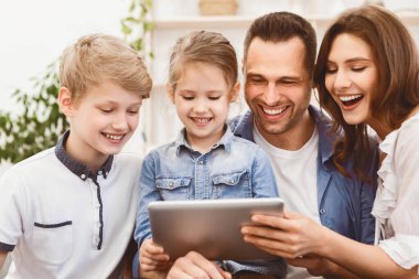 Neşeli Aile Dijital Tablet Kullanıyor, Gülüyor, Koltukta Oturuyor, Evde Birlikte Hafta Sonu Keyfini Çıkartıyor.