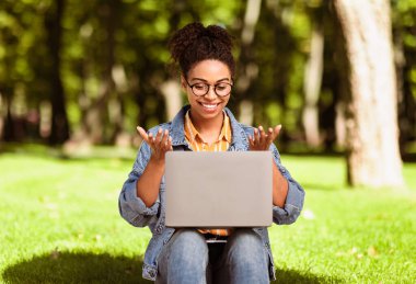 Neşeli Afrikalı Serbest Çalışan Kadın şehir parkının dışında dizüstü bilgisayarla video görüşmesi yapıyor. Her Zaman İrtibat, Uzak İletişim, Çevrimiçi Video Konferansı Konsepti