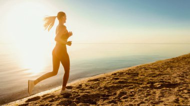 Sportif Bayan. Güneş kumsalında gün ışığında koşan kadının arka görüntüsü, bayrak, kopyalama alanı