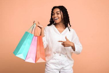 Başarılı Alışveriş Konsepti. Afrikalı Alışverişkolik Kız Bej Stüdyo Arkaplanının Üzerinde Durmakta Mevsimlik Güncellemeleri Gösteren Alışveriş Torbaları.