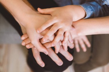 Aile bağı. Aileler ve çocuklar evde el ele tutuşuyorlar. Kırpılmış, Kapalı, Seçici Odaklanma