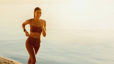 Egzersiz ve spor. Güzel bayan koşucu sahilde koşuyor, kopyalama alanı, afiş