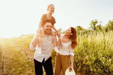Mutlu ebeveynler ve çocuklar yaz ormanlarında birlikte yürüyorlar, baba kızına biniyor, kopyalama alanı.