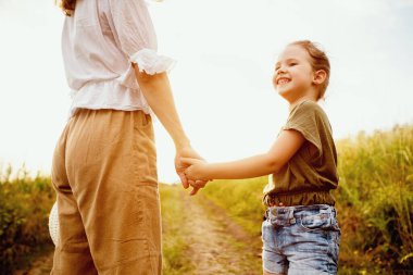 Birlikte olduğumuz anlar. Kızların elini tutan, kırsalda yürüyen genç annenin arka görüntüsü.