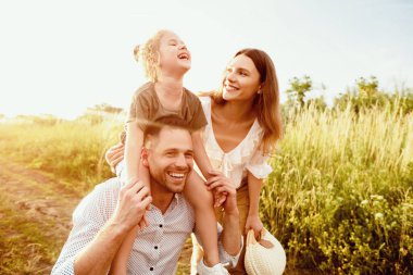 Mutlu anlar. Genç baba bebeğini boynunda tutuyor, çayırda karısıyla yürüyor, boşluğu kopyalıyor.
