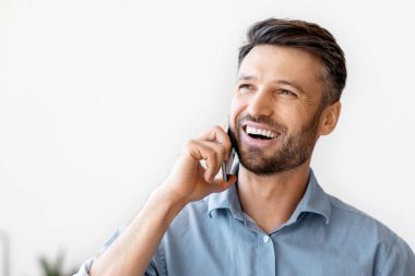 Neşeli bir iş adamı ofisteki işyerinde cep telefonu ve kahveyle dinleniyor, masada oturuyor, cep telefonuyla konuşuyor, ailesiyle konuşuyor, işte mola veriyor, mekanı kopyalıyor.