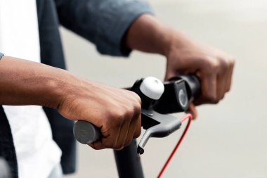 Yaşam tarzı kavramı. Siyah elektrikli scooter 'ın sapını tutan tanınamayan Afrikalı Amerikalı çocuğun yakın çekimi.
