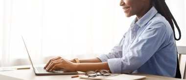 İçişleri Bakanlığı 'nda dizüstü bilgisayarda çalışan gülümseyen Afrikalı Amerikalı kadın, pencere kenarında oturan, klavyede yazan serbest çalışan bayan, uzaktan kumandalı işin tadını çıkaran, kopyalama alanı olan kenar manzaralı kadın.