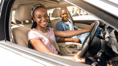 Duygusal, genç, siyah aile babası karı koca hafta sonu araba sürerken kameraya bakıp gülümsüyor, güneş parlıyor. Mutlu Afro-Amerikalı kadın yepyeni beyaz bir araba kullanıyor.