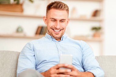 Boş zaman kavramı. Cep telefonu tutan gülümseyen adama yakın plan, ona odaklan, boşluğu kopyala