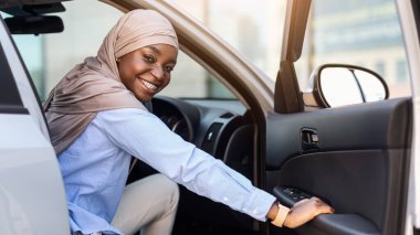 Yeni araba. Mutlu siyah Müslüman iş kadını lüks bir arabaya biniyor, kapıyı açıyor ve sabah işe giderken kameraya gülümsüyor, tesettüre giriyor, kiralık araçların keyfini çıkarıyor, boş alanların keyfini çıkarıyor.