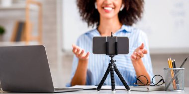 Sınıfta eğitim ve çevrimiçi konferans. Öğretmenim, web kamerasına bakın. Oturma odasının içinde covid-19 salgını sırasında tahtayla birlikte cihazla öğretin.